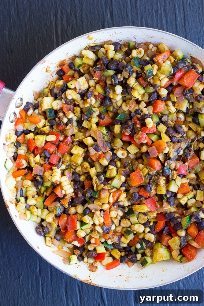 Close-up of vibrant make-ahead enchilada lunch bowls ready for the oven, showcasing fresh vegetables, beans, and corn tortillas.
