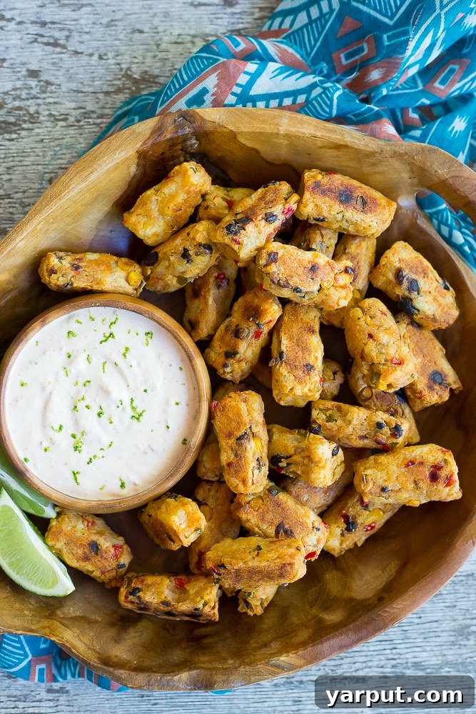 Southwest Potato Bites with Creamy Chipotle Lime Dip 2 Crispy baked Tex-Mex Tater Tots piled high, ready to be dipped into a small bowl of creamy Chipotle Lime Dip, garnished with fresh cilantro.