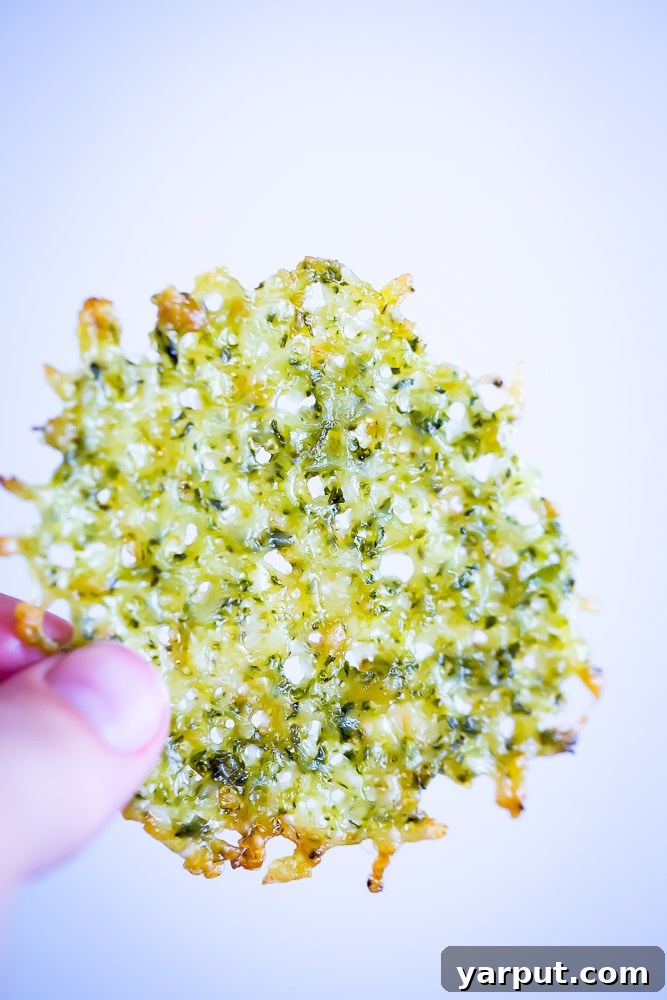 Close-up of baked Two-Ingredient Pesto Parmesan Chips on parchment paper, showcasing their golden crispiness