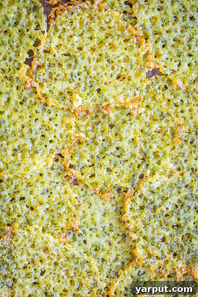 Plate of crispy Two-Ingredient Pesto Parmesan Chips garnished with fresh basil, ready to serve