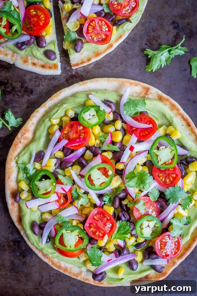 Guac-Topped Pita Bites 2 Freshly prepared Guacamole Pita Pizzas topped with colorful vegetables, ready to be served on a rustic wooden board.