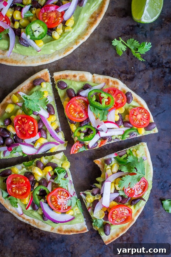 Guac-Topped Pita Bites 4 An overhead view of a beautifully arranged Guacamole Pita Pizza, garnished with fresh herbs and a slice of lime.