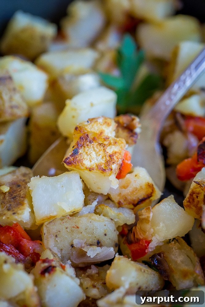 Crispy Golden Morning Potatoes 3 Close-up of freshly cooked crispy breakfast potatoes with diced red pepper and onion in a pan.