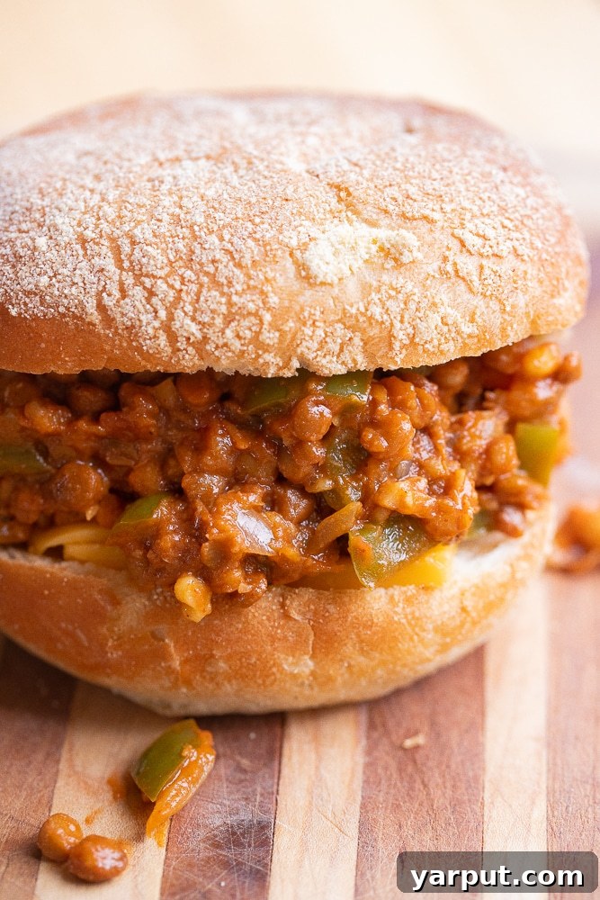 Ultimate Lentil Sloppy Joes 6 Close-up shot of a perfectly assembled plant-based sloppy joe on a bun, showcasing the rich lentil filling.