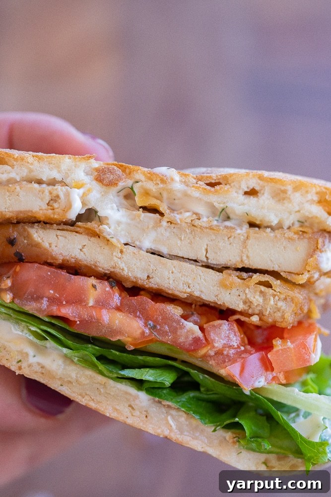 Close-up of a perfectly assembled vegetarian BLT sandwich with crispy tofu bacon