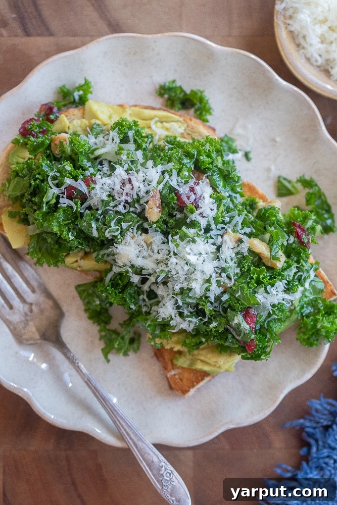 serving plate with a slice of avocado toast topped with kale salad