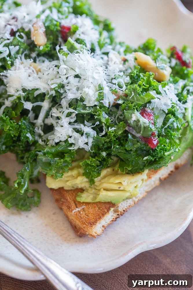 Close up of a slice of toast topped with avocado and kale salad