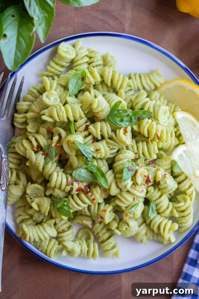 Close up of a plate of green creamy lemon basil pasta topped with red pepper flakes
