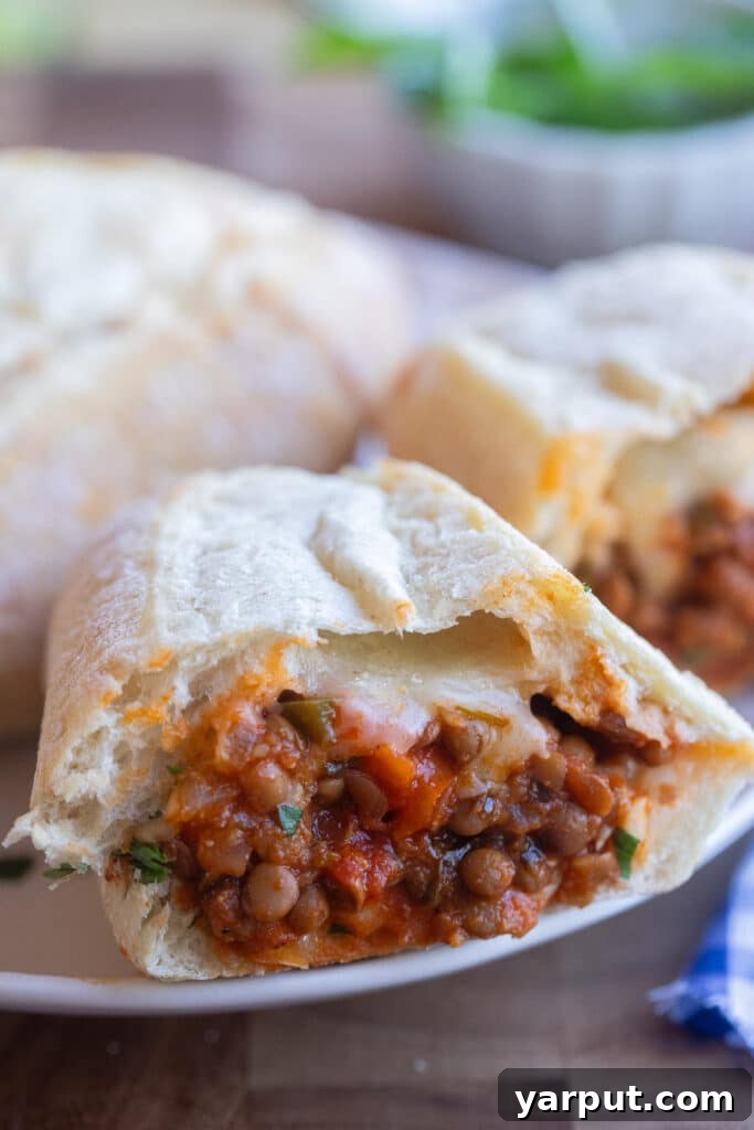 Hearty Lentil Meatball Subs with Savory Marinara 7 Close up of half of a lentil subs sandwich on a plate