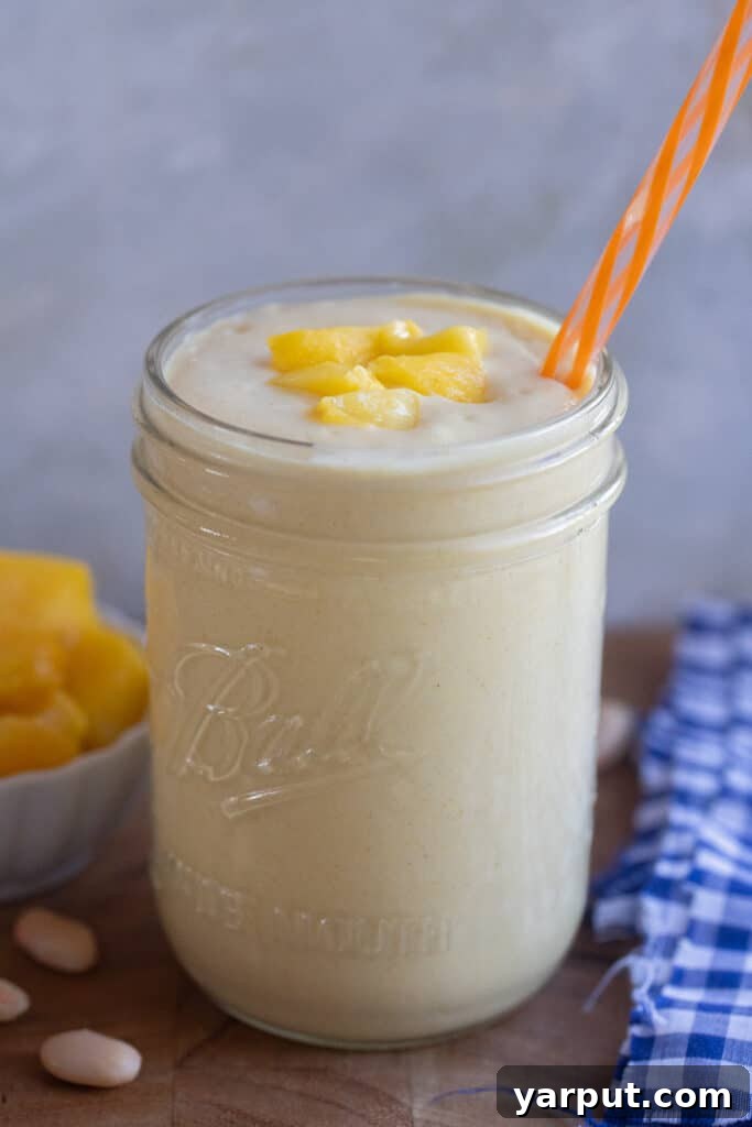 white bean mango smoothie in a cup with a straw