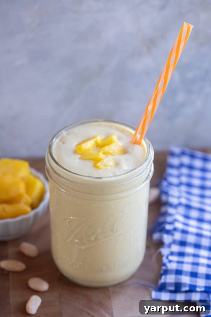 white bean smoothie with mango in a glass jar with a straw