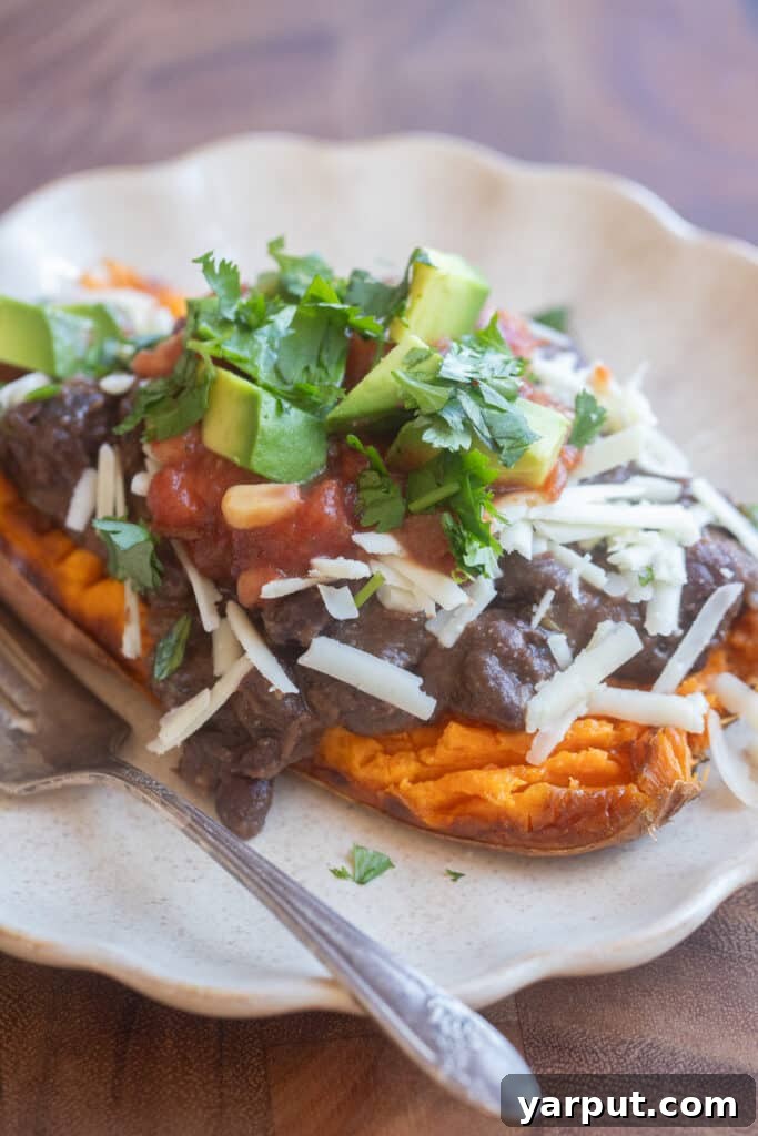 close up of a roasted sweet potato half topped with black beans and cheese
